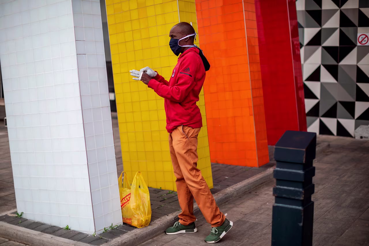 A man wearing a face mask puts on a pair of gloves at the entrance of a shopping mall in Alexandra, Johannesburg, South Africa on April 10.