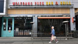 A pedestrian walks past a closed 'Wolfgang Puck Bar & Grill' restaurant  in Los Angeles, California, on March 17, 2020, as the coronavirus epidemic leads to restaurant and school closures as workers work from home in an effort to encourage social distancing. - The White House has suggested gatherings limited to 10 people or less as the number of coronavirus cases across the country passes 5,000 with 100 dead. (Photo by Frederic J. Brown/AFP/Getty Images)